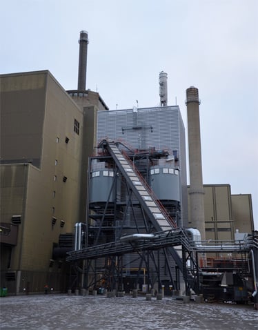 La biomasse séchée circule par le réacteur de gazéification (au 1er plan) afin d’être transformée en biogaz. Ce réacteur mesure 33 mètres de haut et a un diamètre interne de 5 mètres. (©Vaskiluodon Voima)