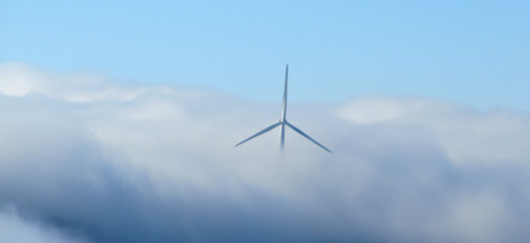 Pales d'une éolienne sortant des nuages